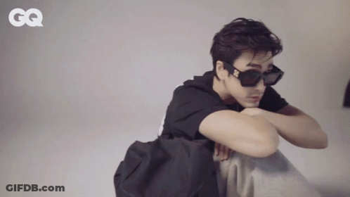 A Man Wearing Sunglasses And A Black Shirt With A Gq Logo On The Bottom GIF
