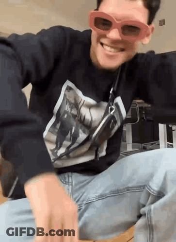 A Man Wearing Sunglasses And A Black Shirt With A Picture On It GIF