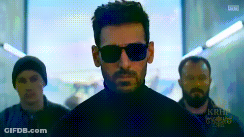 A Man Wearing Sunglasses And A Black Turtleneck Is Standing Next To Two Other Men . GIF