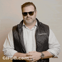 A Man Wearing Sunglasses And A Black Vest With The Word Compass On It GIF