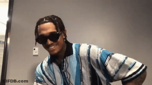 A Man Wearing Sunglasses And A Blue And White Striped Shirt Is Smiling . GIF