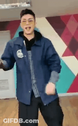 A Man Wearing Sunglasses And A Blue Jacket Is Dancing In Front Of A Wall . GIF