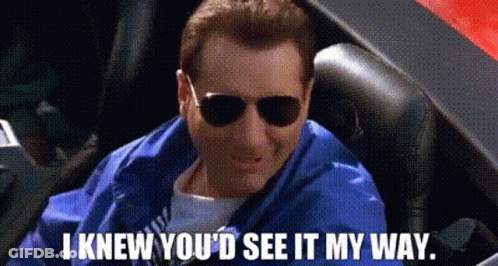 A Man Wearing Sunglasses And A Blue Jacket Is Sitting In A Car . GIF