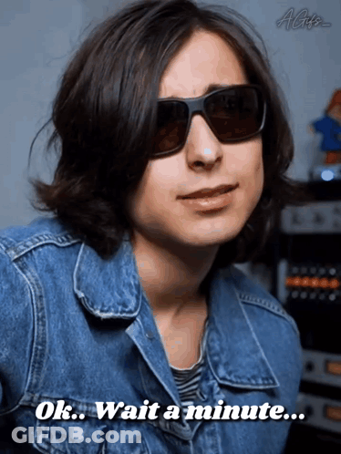 A Man Wearing Sunglasses And A Blue Jacket Says Ok Wait A Minute GIF
