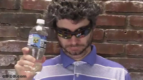 A Man Wearing Sunglasses And A Blue Shirt Is Holding A Bottle Of Water With A Label That Says Atomic On It GIF