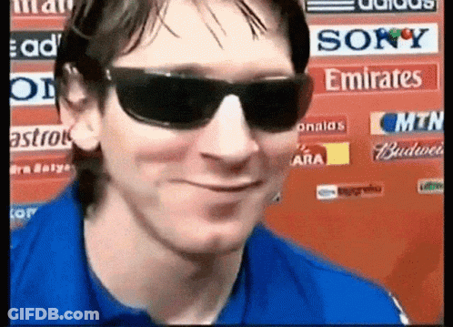 A Man Wearing Sunglasses And A Blue Shirt Is Smiling In Front Of A Sign That Says Sony Emirates GIF