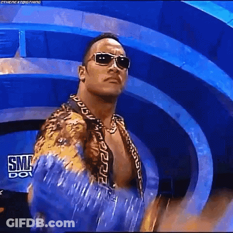 A Man Wearing Sunglasses And A Blue Shirt Is Standing In Front Of A Blue Background . GIF
