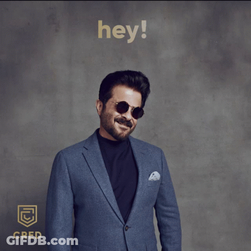 A Man Wearing Sunglasses And A Blue Suit Is Standing In Front Of A Sign That Says " Hey " GIF