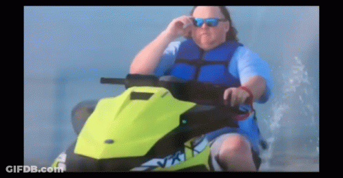 A Man Wearing Sunglasses And A Blue Vest Is Riding A Jet Ski GIF