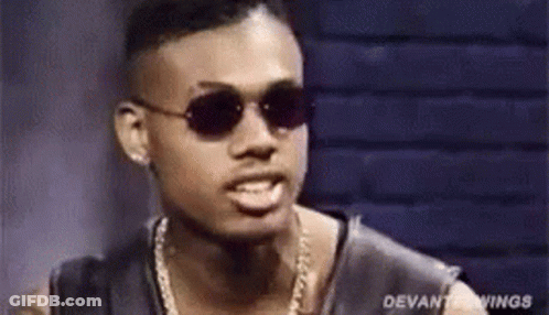 A Man Wearing Sunglasses And A Chain Around His Neck Is Making A Funny Face . GIF