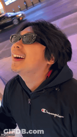 A Man Wearing Sunglasses And A Champion Jacket Smiles GIF
