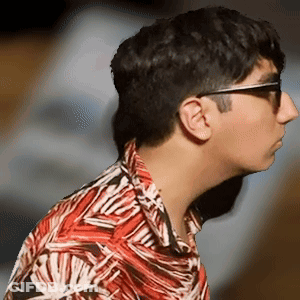 A Man Wearing Sunglasses And A Colorful Shirt Looks To The Side GIF