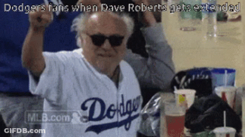 A Man Wearing Sunglasses And A Dodgers Jersey Holds His Fist Up In The Air GIF