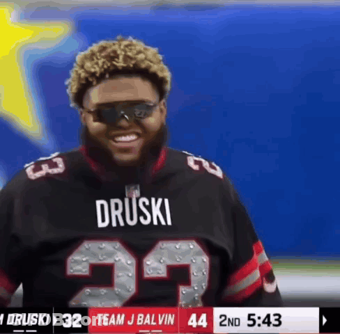 A Man Wearing Sunglasses And A Druski Jersey Is Smiling GIF