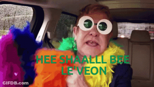 A Man Wearing Sunglasses And A Feather Boa Says " Hee Shaall Bee Le Veon " GIF