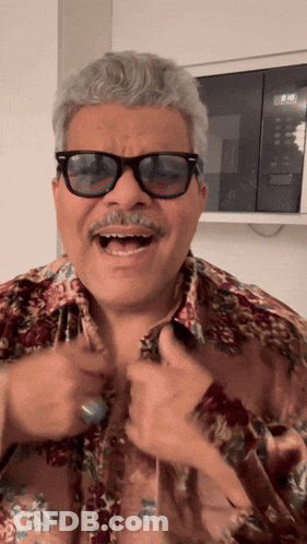 A Man Wearing Sunglasses And A Floral Shirt Laughs GIF