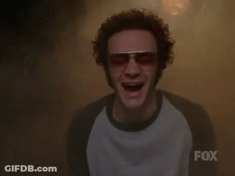A Man Wearing Sunglasses And A Fox Shirt Is Screaming In A Dark Room . GIF