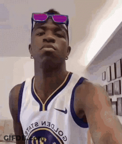 A Man Wearing Sunglasses And A Golden State Warriors Jersey Looks At The Camera GIF