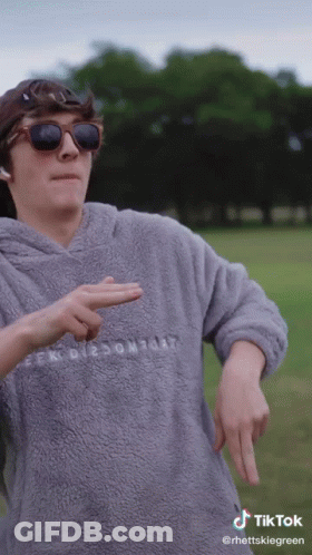 A Man Wearing Sunglasses And A Grey Sweater With The Word Comfort On The Front GIF