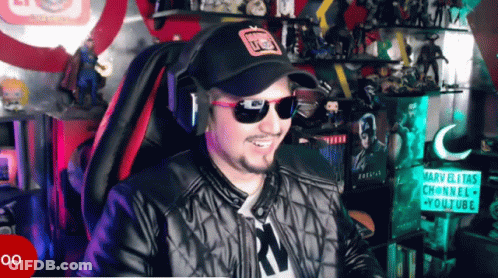 A Man Wearing Sunglasses And A Hat Is Smiling In Front Of A Sign That Says Marvelitas Channel GIF