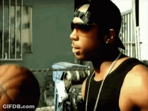 A Man Wearing Sunglasses And A Hat Is Standing In Front Of A Window GIF