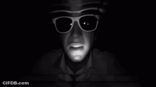 A Man Wearing Sunglasses And A Hat Looks At The Camera GIF