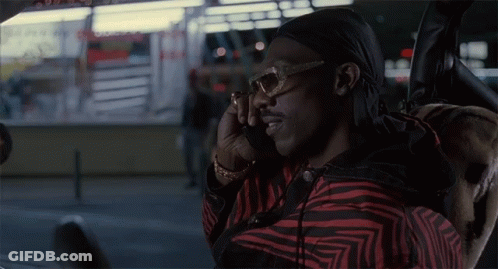 A Man Wearing Sunglasses And A Head Scarf Talks On A Cell Phone GIF