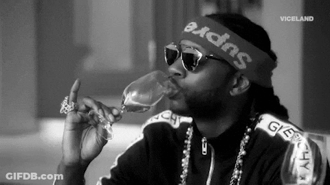 A Man Wearing Sunglasses And A Headband Is Drinking From A Wine Glass . GIF