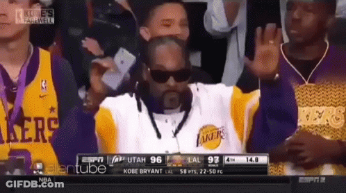A Man Wearing Sunglasses And A Lakers Jersey Waves To The Crowd GIF