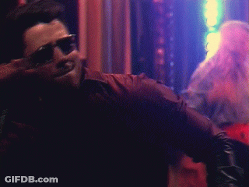 A Man Wearing Sunglasses And A Leather Jacket Is Smiling GIF