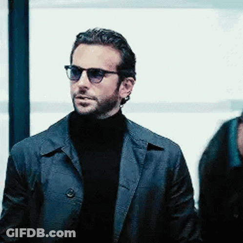 A Man Wearing Sunglasses And A Leather Jacket Is Standing Next To A Man Wearing A Turtleneck . GIF