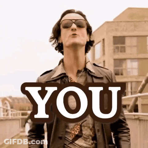 A Man Wearing Sunglasses And A Leather Jacket Stands In Front Of A Sign That Says " You " GIF