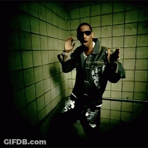 A Man Wearing Sunglasses And A Leather Jacket Stands In Front Of A Tiled Wall GIF