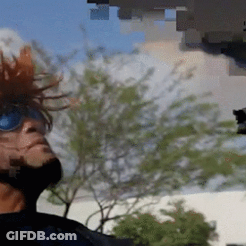A Man Wearing Sunglasses And A Mohawk Looks Up Into The Sky GIF
