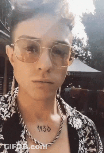 A Man Wearing Sunglasses And A Necklace Has A Tattoo On His Chest That Reads 1130 GIF