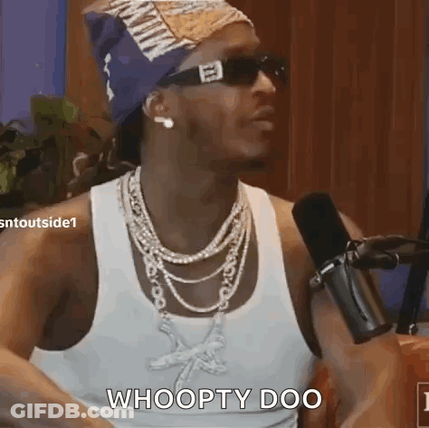 A Man Wearing Sunglasses And A Necklace Is Sitting In Front Of A Microphone And Says Whoopty Doo . GIF