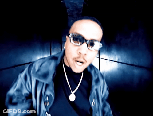 A Man Wearing Sunglasses And A Necklace With A Pendant GIF