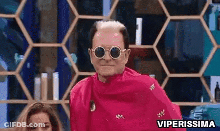 A Man Wearing Sunglasses And A Pink Shirt Is Standing In Front Of A Honeycomb Shelf . GIF