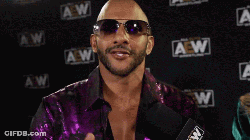 A Man Wearing Sunglasses And A Purple Shirt Says " It 'S About Damn Time " GIF