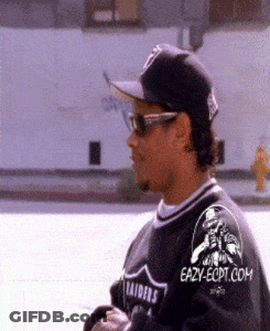 A Man Wearing Sunglasses And A Raiders Jersey Is Walking Down The Street GIF