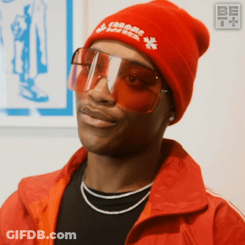 A Man Wearing Sunglasses And A Red Beanie With Chrome Hearts On It GIF