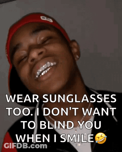 A Man Wearing Sunglasses And A Red Hat Is Smiling GIF