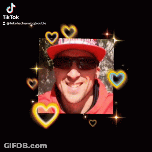 A Man Wearing Sunglasses And A Red Hat Is Smiling For The Camera GIF