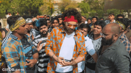 A Man Wearing Sunglasses And A Red Headband Is Surrounded By People GIF