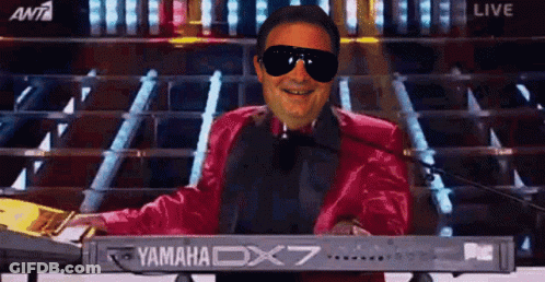 A Man Wearing Sunglasses And A Red Jacket Is Playing A Yamaha Dx7 Keyboard GIF