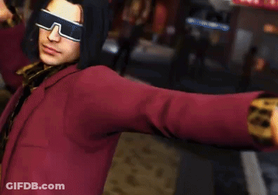 A Man Wearing Sunglasses And A Red Jacket Is Standing In A Street . GIF