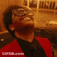 A Man Wearing Sunglasses And A Red Jacket Looks Up At The Sky GIF