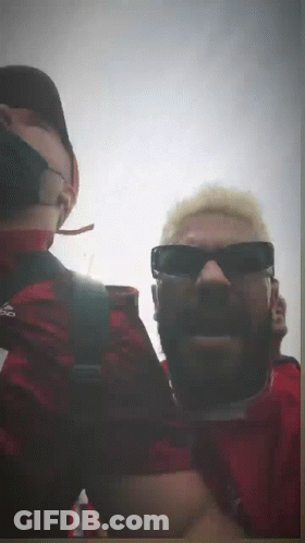 A Man Wearing Sunglasses And A Red Shirt With Adidas On It GIF