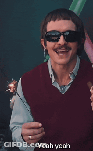 A Man Wearing Sunglasses And A Red Vest Is Holding A Sparkler And Saying Yeah Yeah GIF