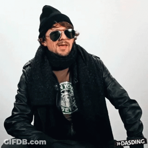 A Man Wearing Sunglasses And A Scarf Has A Dasding Belt Around His Waist GIF